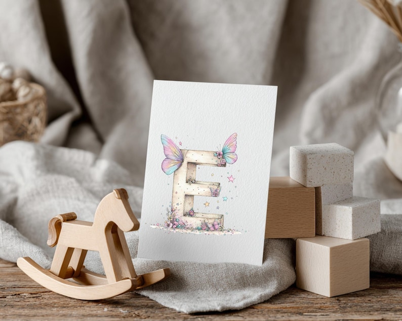May include: A watercolor illustration of the letter "E" adorned with butterfly wings and floral accents. The letter is on a white card, with a wooden rocking horse and blocks in the foreground. Soft pastel colors are used.