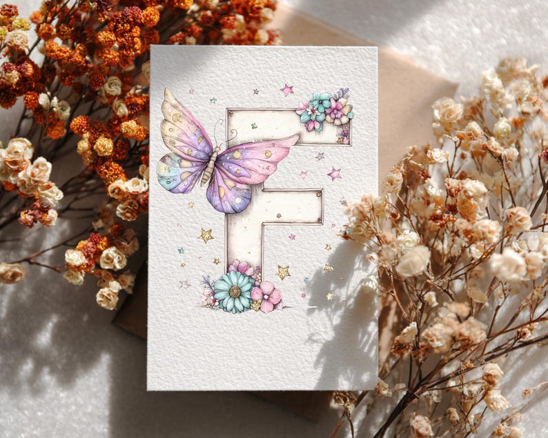 May include: A watercolor greeting card featuring a butterfly with purple, pink, and blue wings. The butterfly is positioned on a letter "F" decorated with flowers and stars. The card is on a neutral background with dried flowers.
