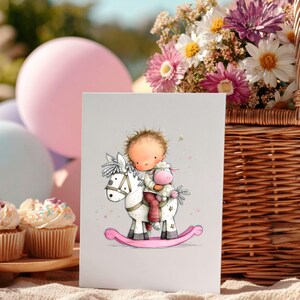 May include: A greeting card featuring a whimsical illustration of a child riding a rocking horse, accompanied by a stuffed animal. The card has a light gray background, with a pink rocking horse and a child wearing red pants. A basket of flowers and cupcakes are in the background.
