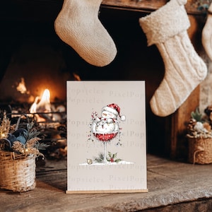 Peut inclure: Une impression rectangulaire pr&eacute;sentant une illustration fantaisiste d'un bonhomme de neige portant un bonnet de P&egrave;re No&euml;l rouge, assis dans un grand verre &agrave; vin rempli de liquide rouge. Il tient un sucre d'orge, entour&eacute; de guirlandes.