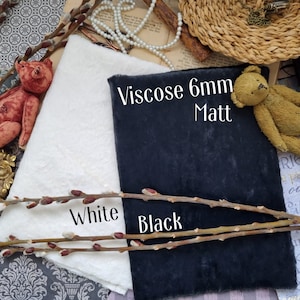 以下が含まれることがあります： 白い生地と黒い生地の2つの生地見本で、"Viscose 6mm Matt"というテキストと、その下に"White"と"Black"という単語が書かれています。