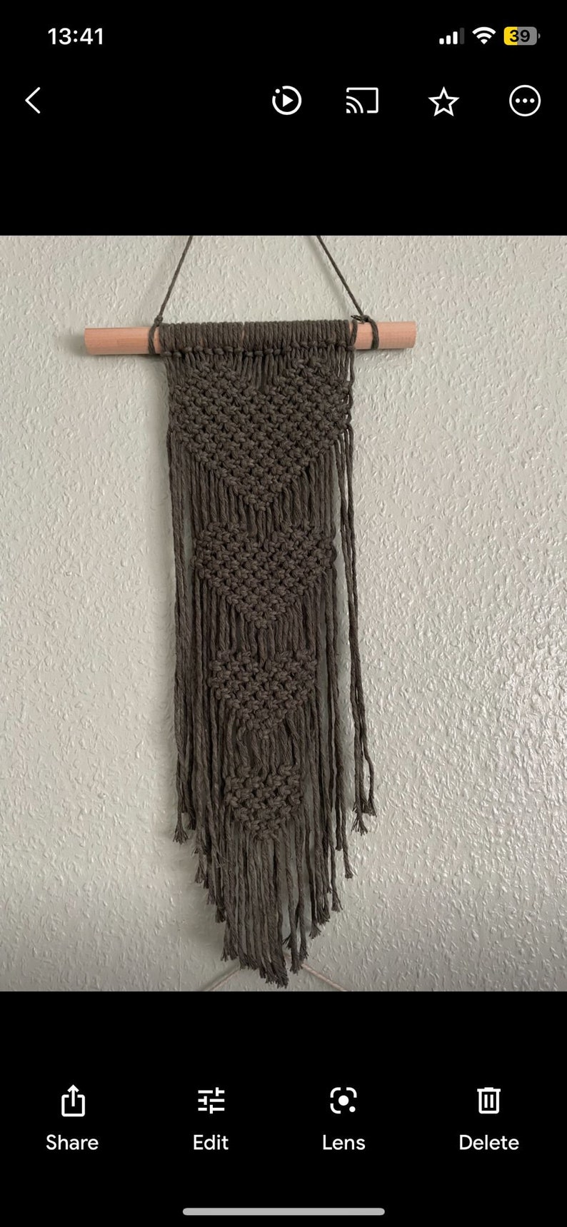 Peut inclure: Une suspension murale en macram&eacute; vert fonc&eacute; avec un motif g&eacute;om&eacute;trique et des franges. La suspension est fix&eacute;e &agrave; une baguette en bois.