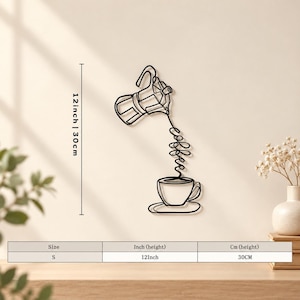 Puede incluir: Una pieza de arte mural de metal negro con un dibujo de línea continua de una cafetera moka vertiendo líquido en una taza, con la palabra coffee escrita en cursiva. La pieza mide 30 cm de altura según se indica en el texto.