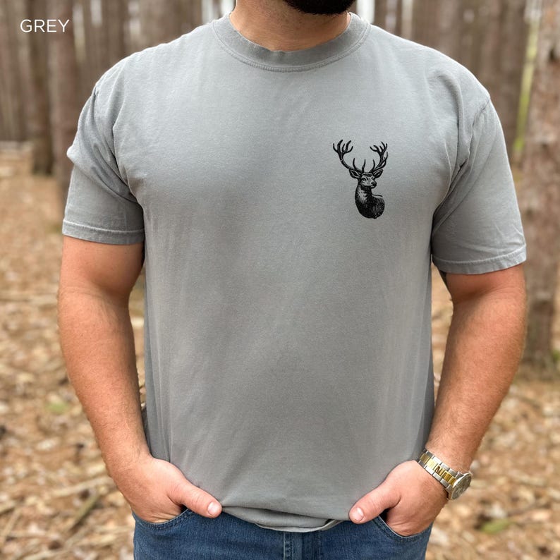 May include: A grey t-shirt with a black deer head graphic on the front.