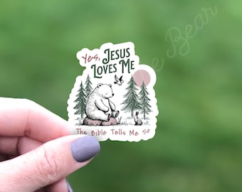 Peut inclure: Un autocollant blanc avec un ours polaire assis dans une forêt avec un oiseau et un lapin. L'autocollant dit "Oui, Jésus m'aime. La Bible me le dit."