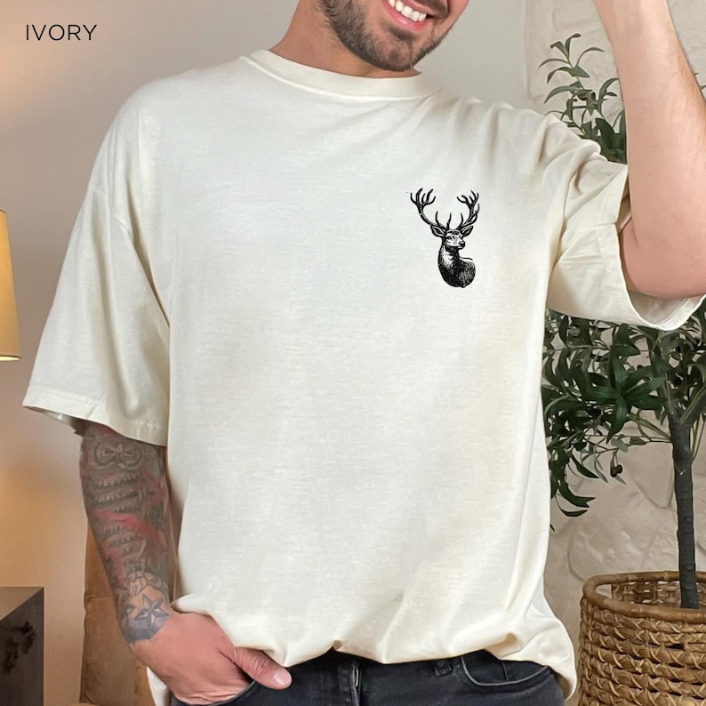 May include: A white t-shirt with a black deer silhouette graphic on the front. The shirt is made of a soft, comfortable fabric and has a relaxed fit.