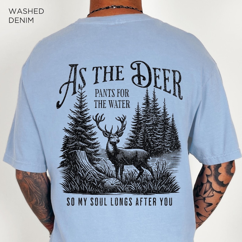 May include: A light blue t-shirt with a black graphic print of a deer in a forest. The text "As the Deer" is above the deer and the text "Pants for the Water" is below the deer. The text "So my soul longs after you" is at the bottom of the graphic.