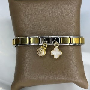 May include: A gold and silver charm bracelet with a seashell and a four-leaf clover charm.