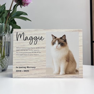 Könnte beinhalten: Ein hölzerner Gedenkrahmen für Haustiere mit dem Namen "Maggie" in Schreibschrift. Der Rahmen enthält ein Foto einer Katze und den Text "In Loving Memory 2010-2025". Ein Gedicht ist ebenfalls enthalten.