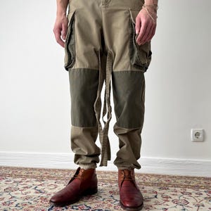 Könnte beinhalten: Eine braune und grüne Cargohose mit mehreren Taschen und einem Bindedetail an der Taille.