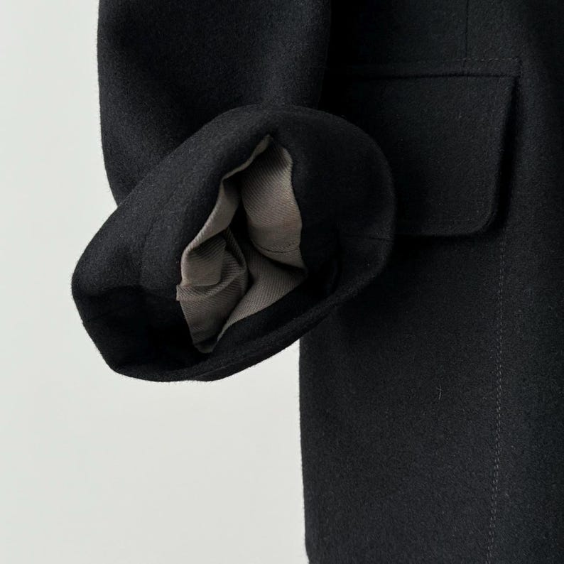 Puede incluir: Primer plano del forro de lana negro de una manga de chaqueta. El forro est&aacute; del rev&eacute;s, mostrando las costuras y la textura de la tela.