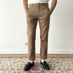 May include: A pair of brown chino pants with a straight leg fit. The pants have a belt loop waistband and front pockets.