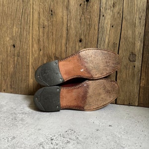 May include: The bottom of a pair of brown leather shoes with a black rubber sole. The shoes are size 3.
