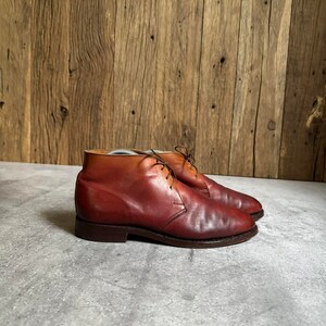 May include: A pair of brown leather ankle boots with laces. The boots have a rounded toe and a low heel.