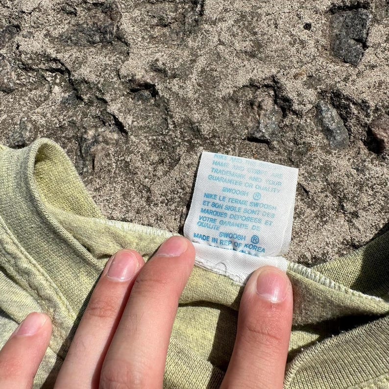Peut inclure: Un t-shirt vert clair avec une &eacute;tiquette blanche qui indique "Nike Le Terme Swosh et Bon Sigle Bont Des Marques Deposees et Votre Garantie De Qualite Swoosh Made in Rep of Korea".