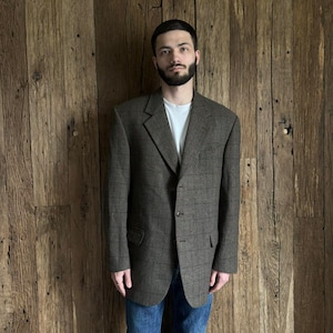 May include: A brown plaid blazer with a single button closure. The blazer has a notched lapel and flap pockets.