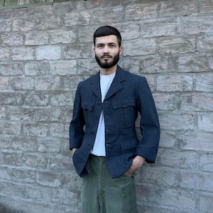 May include: A dark blue blazer with a button-up front and multiple pockets. The blazer has a slightly textured fabric and a relaxed fit.