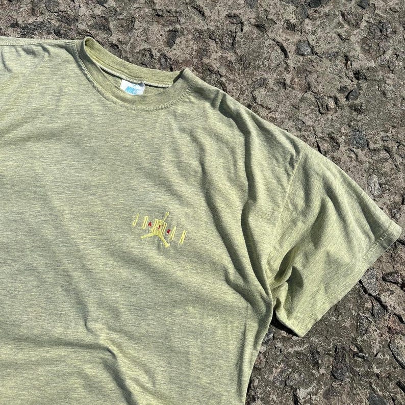 Peut inclure: Un t-shirt vert clair avec un logo Jordan brod&eacute; en jaune sur le devant.