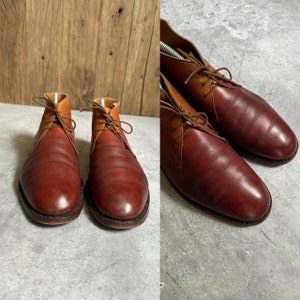 May include: A pair of brown leather ankle boots with laces. The boots have a light brown shade on the top and a darker brown shade on the bottom.