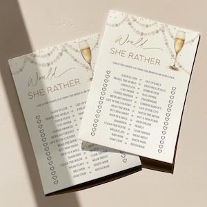 May include: Two ivory-colored bridal shower game cards with gold text and champagne glass illustrations. The cards feature a "Would She Rather" game with various choices. Pearl and champagne illustrations decorate the top.
