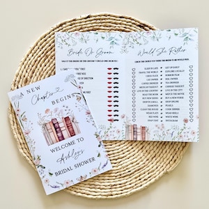 May include: Bridal shower game set featuring two cards with floral and book illustrations. One card reads "A New Chapter Begins" and welcomes guests to Ashley's bridal shower. The other card has "Bride or Groom" and "Would She Rather" questions.