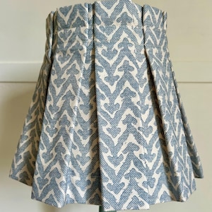 Op de afbeelding: Een conische lampenkap met een blauw-wit zigzagpatroon. De stof is geplooid, wat een textuureffect creëert. Hij staat op een groene lampenvoet. De hoogte is ongeveer 20 cm.