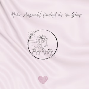 May include: A light pink background with a heart at the bottom and text at the top. A black circular logo features a hand holding a gift box with a bow, and the words "the joy of gifting."
