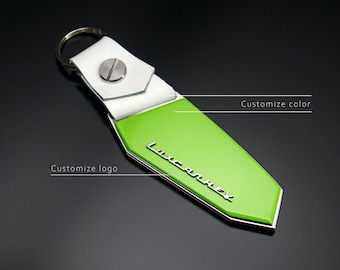 May include: A green and white leather keychain with the word "LUXCARNEX" in silver lettering. The keychain has a white leather strap and a silver ring.