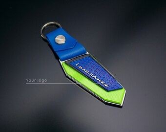 May include: A blue and green leather keychain with a silver metal loop and a silver metal plate with the text "LUXCARNEX" in black lettering.