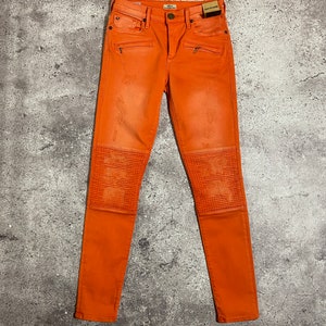 May include: Orange skinny jeans with zipper details and knee pads.