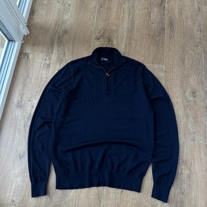 Puede incluir: Suéter azul marino de manga larga con cierre de cremallera de un cuarto. El suéter tiene dobladillo y puños acanalados. El cuello es alto. El suéter está hecho de un material suave y cómodo.