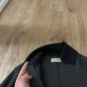 Op de afbeelding: Een donker antracietgrijze jas met een contrasterende zwarte kraag van geribd breiwerk. Het kledingstuk heeft een wit binnenlabel met de tekst Falconeri made in Italy bij de halslijn en toont een constructie van gestructureerde stof.