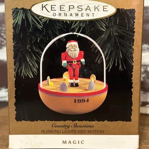 Könnte beinhalten: Eine Keepsake Ornament-Box mit einer Weihnachtsdekoration. Das Ornament zeigt den Weihnachtsmann in einem roten Anzug, der auf einer Bühne steht. Auf der Box steht "Country Showtime" und "Blinking Lights and Motion". Das Jahr "1994" ist ebenfalls sichtbar.