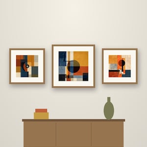May include: Three framed square wall art prints featuring geometric compositions of circles and blocks in shades of orange, blue, and cream. The text reads Crestline Color Co. Circle & Block. Below, a brown sideboard holds two boxes and a vase.