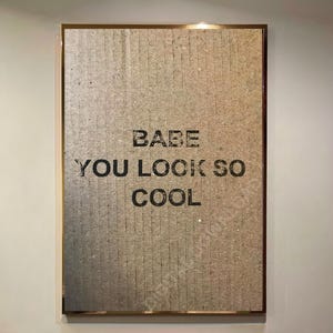 Peut inclure: Une affiche encadrée dorée avec un fond texturé. L'affiche porte le texte "BABE YOU LOOK SO COOL" imprimé en noir.