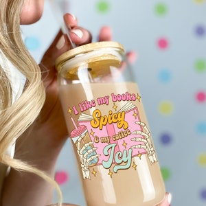 May include: A clear glass jar with a wooden lid and a pink and white design. The jar has the text "I like my books Spicy & my coffee Icy" printed on it.