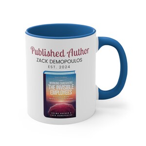 May include: White ceramic mug with a blue interior and handle. The mug features the text "Published Author ZACK DEMOPOULOS EST. 2024" in burgundy script. Below the text is a book cover image with the title "WORKING CAREGIVERS THE INVISIBLE EMPLOYEES".
