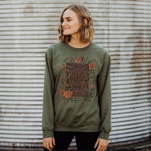 May include: A green sweatshirt with a floral design and the text "Dibs on the Villain" printed on the front.