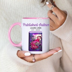 May include: White ceramic mug with a pink handle and interior. The mug features the text "Published Author" and "LAURA LINN EST. 2023". The mug also displays a book cover image titled "A Wildflower for the Duke" by Laura Linn.