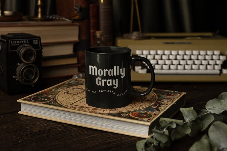 Black coffee mug with shades of gray text that says, “Morally gray is my favorite color”
