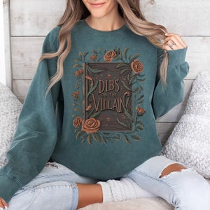 May include: Teal sweatshirt with a floral design and the text "Dibs on the Villain" printed on the front.