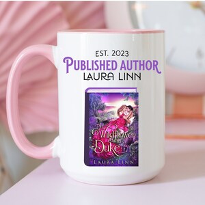 May include: White ceramic mug with a pink handle and rim. The mug features the text "EST. 2023 PUBLISHED AUTHOR LAURA LINN" and a book cover with the title "A Wildflower for a Duke" by Laura Linn.