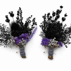 Könnte beinhalten: Zwei florale Ansteckblumen bestehend aus einer Mischung aus getrocknetem schwarzem Blattwerk, kleinen schwarzen Beeren, violettem Statice und silberfarbenem Schleierkraut. Jedes Arrangement ist am Fuß mit einem grauen Samtband fest umwickelt.