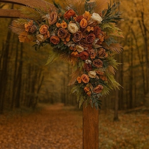 Könnte beinhalten: Hochzeitsbogen aus Holz, verziert mit einem Blumengesteck. Die Blumen sind in Orange-, Rost- und Cremetönen gehalten, mit grünem Laub. Der Bogen steht vor einem Wald mit einem Pfad.