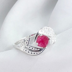 Puede incluir: Un anillo de plata con una piedra preciosa rosa engastada en un diseño de hoja.
