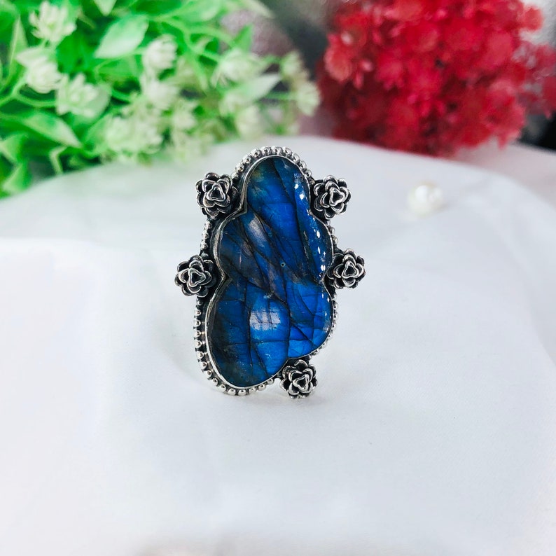 May include: A silver ring with a large blue labradorite gemstone set in a floral design.