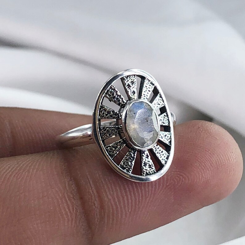 May include: A silver ring featuring a moonstone set within a sunburst design.