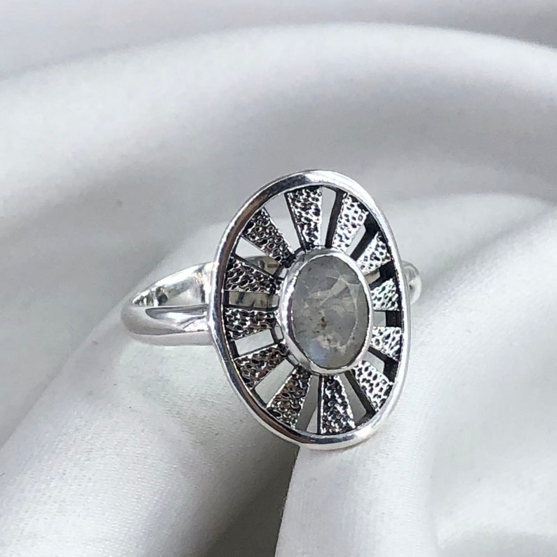 May include: A silver ring featuring a moonstone set within a sunburst design.