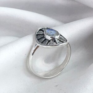 May include: A silver ring featuring a moonstone set within a sunburst design.