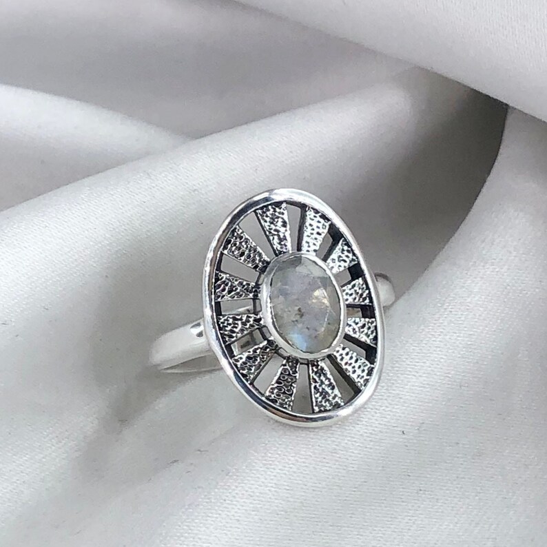May include: A silver ring featuring a moonstone set within a sunburst design.